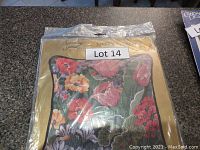 Photo of unopened needlepoint pillow kit in original packaging showing floral pillow image.