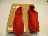 Pair of red felt slippers displayed on top of the original cardboard box