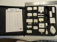Overview angle showing multiple Targus travel plug adapters arranged in foam insert in black case along a ruler for scale.