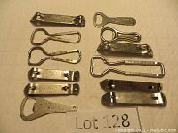 Twelve vintage metal bottle openers displayed on flat surface with Lot 128 label, showing variety of brands and shapes.