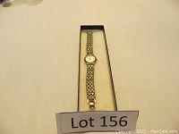 Full view of the gold toned women's Citizen quartz watch in rectangular box with lot number.