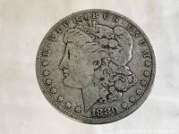 Front side of the 1880 Morgan Silver Dollar showing Lady Liberty, date, and surrounding inscriptions.
