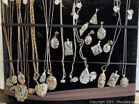 Overhead view of multiple granite pendants and metal chains laid out on black display panel