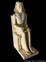 Front left angle view of the cream-colored resin Egyptian Pharaoh statue seated on a throne with detailed decoration.