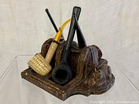 Front angle view showing three smoking pipes in the carved pipe holder with Scotty dog figures on each side.