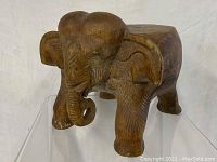 Front side view of the carved wooden elephant plant stand showing detailed trunk, ears and front legs.