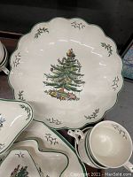 Large scalloped-edge round serving platter with Christmas tree motif alongside cups and saucers.
