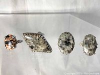 Front view of four sterling silver rings with granite cabochons displayed in a row