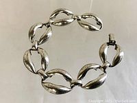 Sterling silver vintage Danecraft bracelet arranged in a circular form on a neutral background with visible patina and clasp detail.