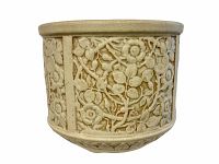 Stoneware planter showing embossed floral and vine motifs on light beige surface.