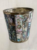 Photo of the cup showing the abalone shell inlay on the brass exterior with visible tarnish and wear.