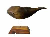 Side view of vintage carved right whale showing smooth dark wood grain and minimal detail.