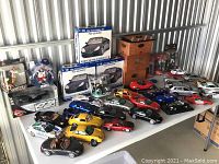 Wide view of die-cast and sports figures lot showing boxed Porsche kits, loose cars, sports figures and wooden storage box.