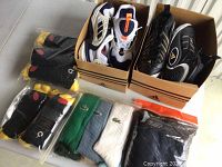 Adidas running shoes in white and black inside boxes, with multiple packs of socks including black/yellow and Lacoste brand socks in various colors in front and to side of boxes.