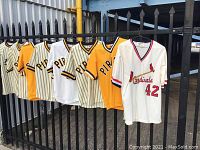 Seven jerseys hung on fence: six Pirates and one Cardinals jersey.