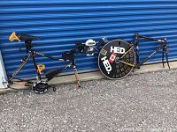 Both frames side by side with attached components and disc wheel leaning against storage unit door