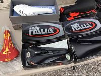 Five saddles in boxes arranged on table.