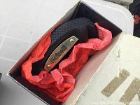 Cinelli saddle in small white box with red tissue paper, black perforated cover and brass Cinelli nameplate visible