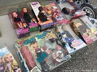 Overview of eleven unopened Bratz dolls and playsets on outdoor surface