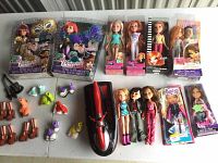 Overview of 6 boxed dolls, 4 loose dolls, multiple pairs of shoes, two guitars, one boat