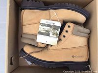 Photo of pair of tan Columbia brand hiking boots inside original box with attached informational tag detailing comfort system.