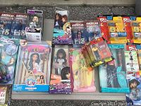 Overview of various boxed dolls and figures laid out on table