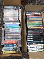 Overview of two cardboard boxes filled with DVD box sets and cases