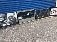 Four framed art pieces leaning against a blue metal door, showing overall size and setup