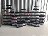 Large lot of Hot Wheels NASCAR die-cast cars arranged in clear plastic display cases stacked on top of each other in columns and rows.