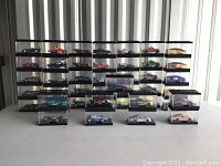Full lot shot showing multiple columns of display cases each containing a Hot Wheels racing model car.