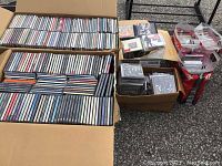 Two large cardboard boxes and smaller containers filled with audio CDs in jewel cases.