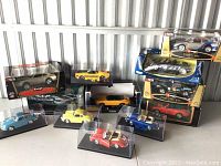 Group shot of ten model cars in original boxes and display cases
