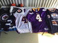 Group of five jerseys displayed flat showing front numbers and logos.