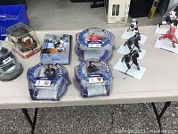 Table display of collectible NHL and NFL sports action figures and mini helmets.