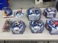 Top view photo of entire sports collectible lot showing all figures, helmet, and their packaging on table in a garage setting