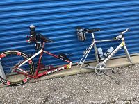 Both red and white and silver Nineteen frames leaning against storage unit, showing overall condition and included parts