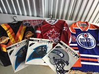 Lot overview showing three hockey jerseys and four NFL team magnets in packaging