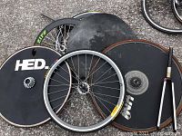 Mixed bike wheels and disc covers on asphalt including HED disc wheel, Zipp skins, spoked wheels, freewheel and pump