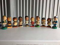 Front view of all 10 bobbleheads aligned on table