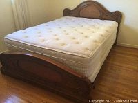 Full view of queen size bed frame with mattress showing headboard and footboard carved wooden frame