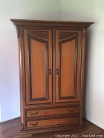Full view of medium brown wooden cabinet with two doors and two drawers, showing overall shape and condition.