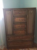 Full front view of wooden chest of drawers with five central drawers and two side compartments.