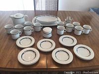 Full set laid out on table showing cups, plates, teapot, sugar bowl and serving dish