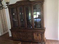 Front view of large wooden china cabinet with glass doors showing display shelves and wooden drawers below.