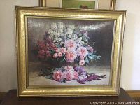 Framed floral oil painting featuring pink, white, and purple flowers in an ornate gold frame.