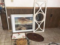 Photo showing framed art, wooden mirror frame, ceramic tiles, woven basket tray, and wooden trays grouped near a wood-paneled wall