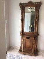 Full front view of the wooden hall tree showing mirror, turned columns, gallery top and base shelf
