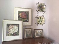 View of two large Kathryn White framed floral prints and two smaller framed prints on a wooden surface