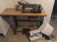 Singer Model 40 D300A sewing machine on wooden tabletop with metal legs and foot pedal beneath.