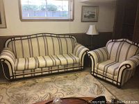 View of matching sofa and armchair in living room, showing brown and beige striped fabric and curved wooden armrest design